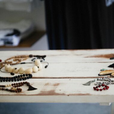A diverse display of handcrafted wooden jewelry and beads on a rustic table indoors.