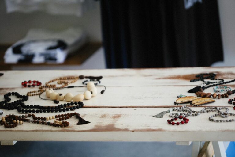 A diverse display of handcrafted wooden jewelry and beads on a rustic table indoors.