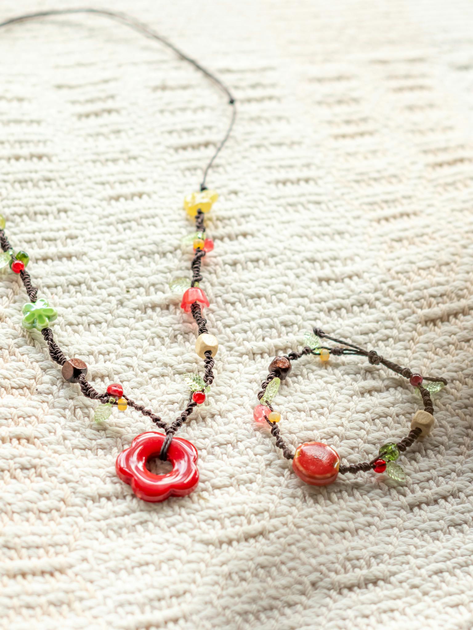 A vibrant handmade beaded necklace and bracelet set on a textured background.