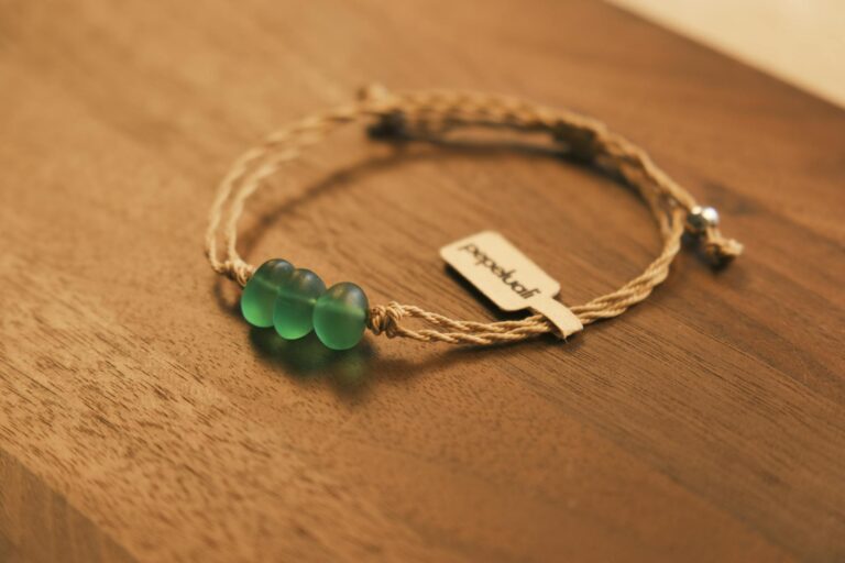 Close-up of a handcrafted bracelet with green glass beads on a wooden table.