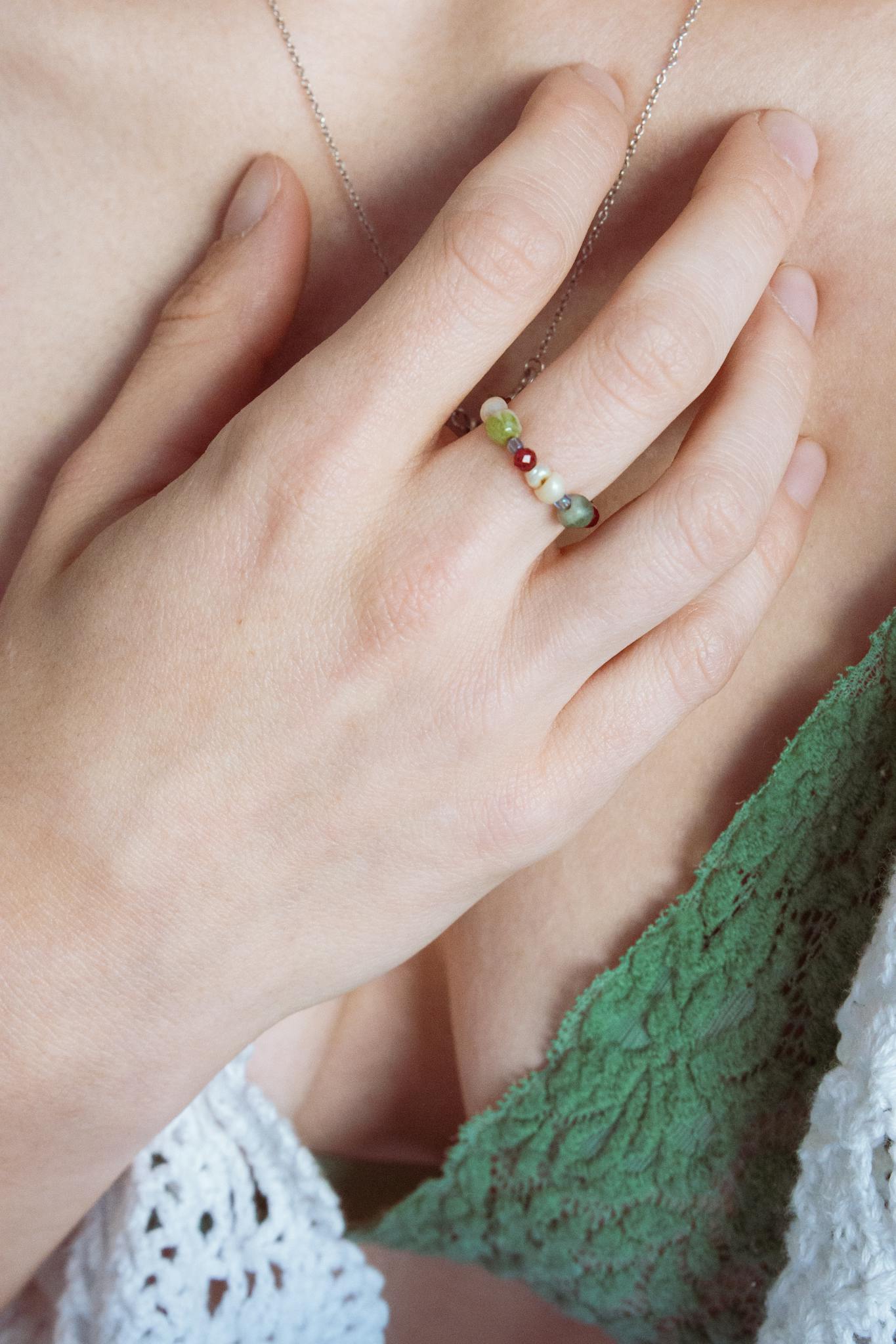 Close-up of a woman's hand wearing a colorful beaded ring, showcasing artisan craftsmanship.