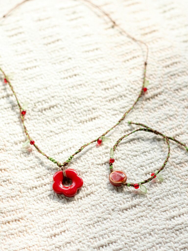 Elegant red flower pendant necklace and bracelet set on textured fabric.
